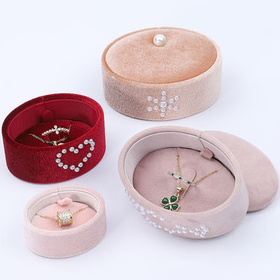 Une petite boîte à bagues en velours ovale, une boîte à bagues en perles.