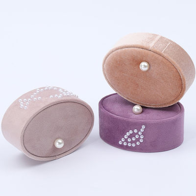 Une petite boîte à bagues en velours ovale, une boîte à bagues en perles.